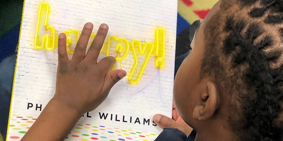 Child Reading a Book Titled Happy