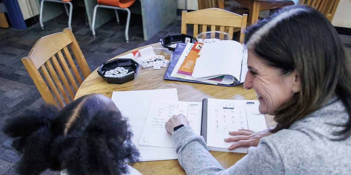 Woman Helping Child With Letters
