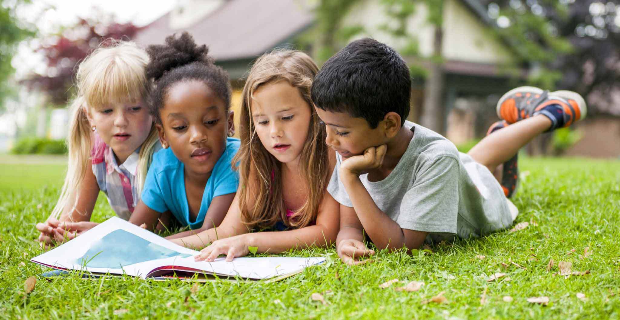 Childern Reading a Book in the Grass